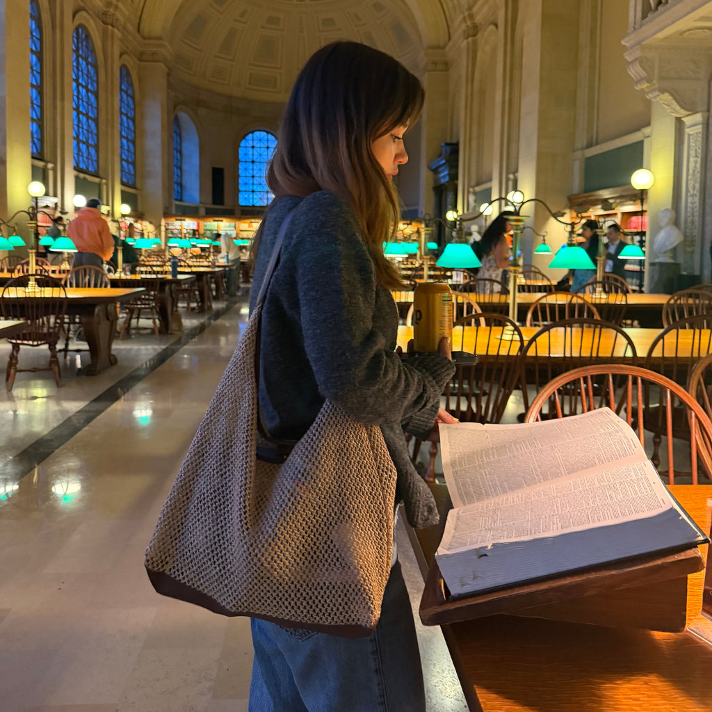 Side view of girl with straw woven shoulder bag in the library