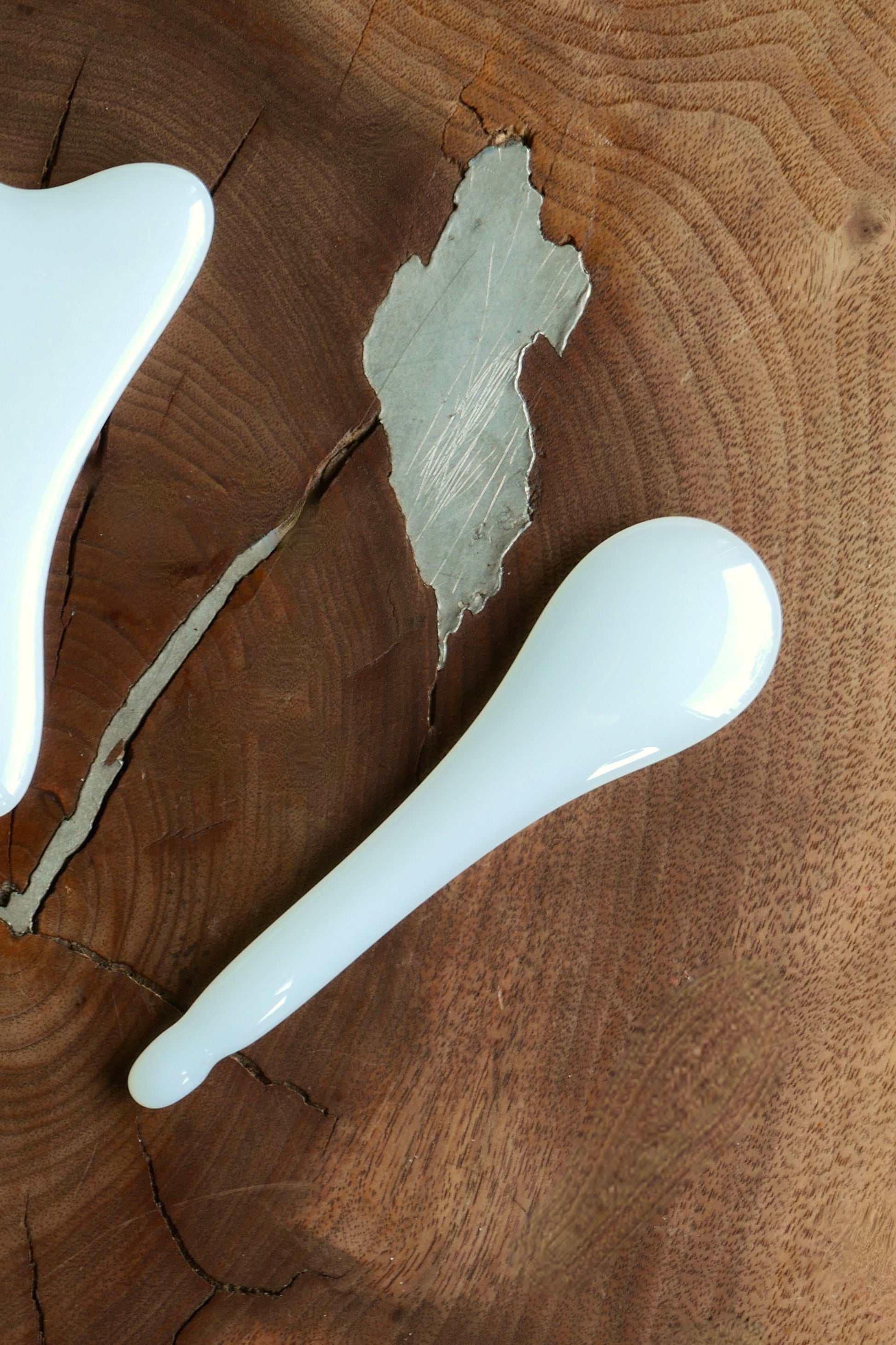Two gua sha tools on a wooden surface